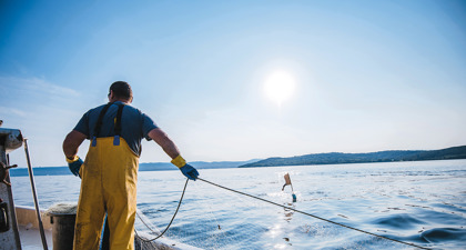 Fisherman in yellow oilskins pulling up his trawler net