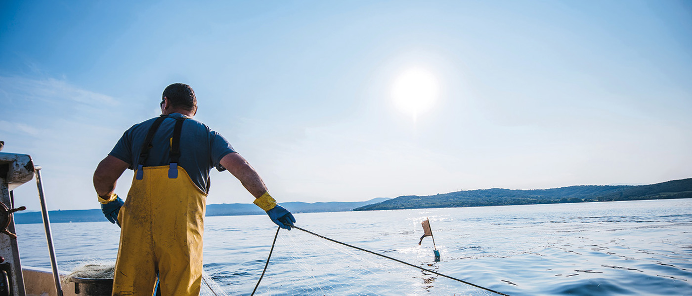 Fisherman in yellow oilskins pulling up his trawler net