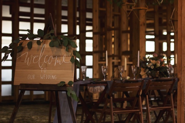 Welcome to our wedding sign in foreground of a rustic wedding reception