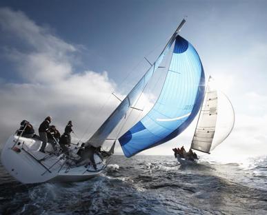 Sailing boat on a rough sea tipping to the right side with men standing on the deck