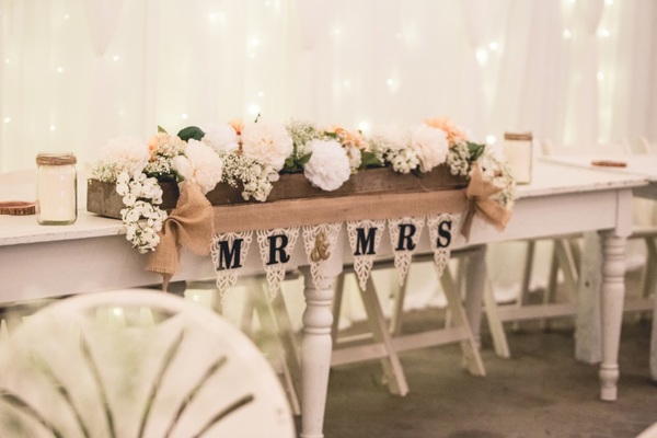 Mr and mrs bunting under a spray of flowers at wedding reception