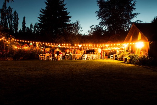 External view of wedding reception at night with fairy lights outside a barn