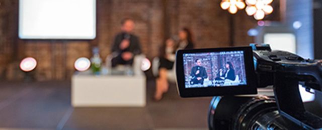 Digital camera's digital screen view of two people talking on soft chairs in a TV studio